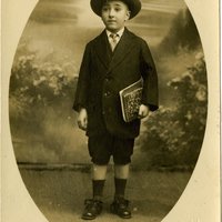 'Soeiro Pereira Gomes com 7 anos, de fato e chapéu e com cadernos debaixo do braço', cerca de 1916